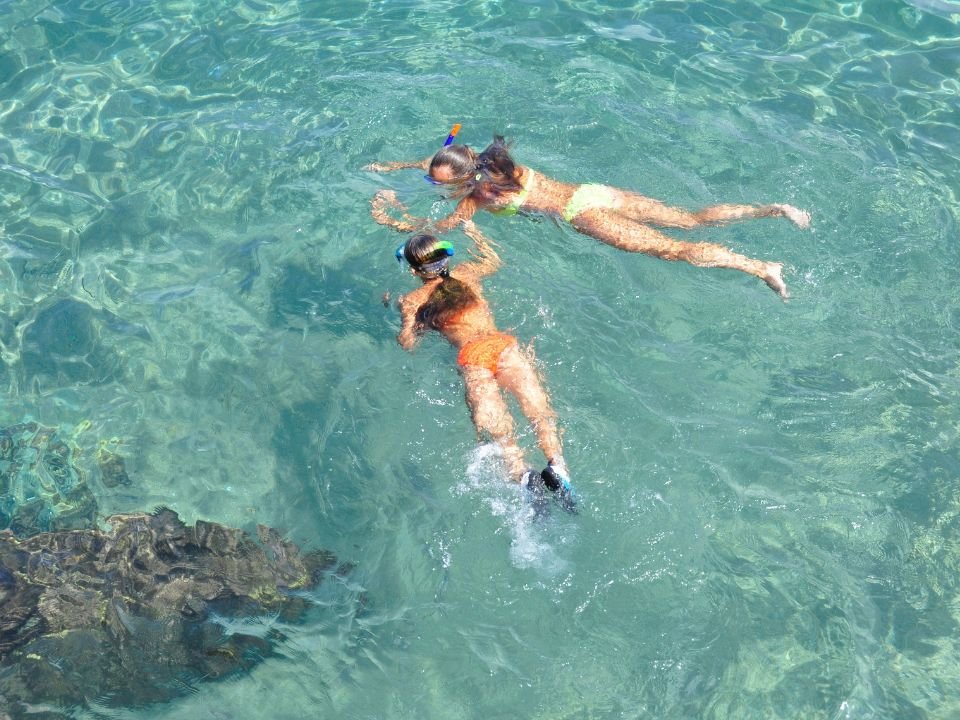 Famiglia che fa snorkeling insieme in acque tranquille, seguendo le norme di sicurezza